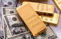 Finance Brokerage – gold spot price: overhead shot of gold bars on top of dollar bills.