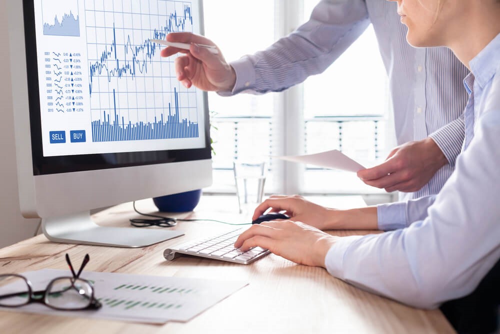 Two persons discussing and looking at graphs – Finance brokerage