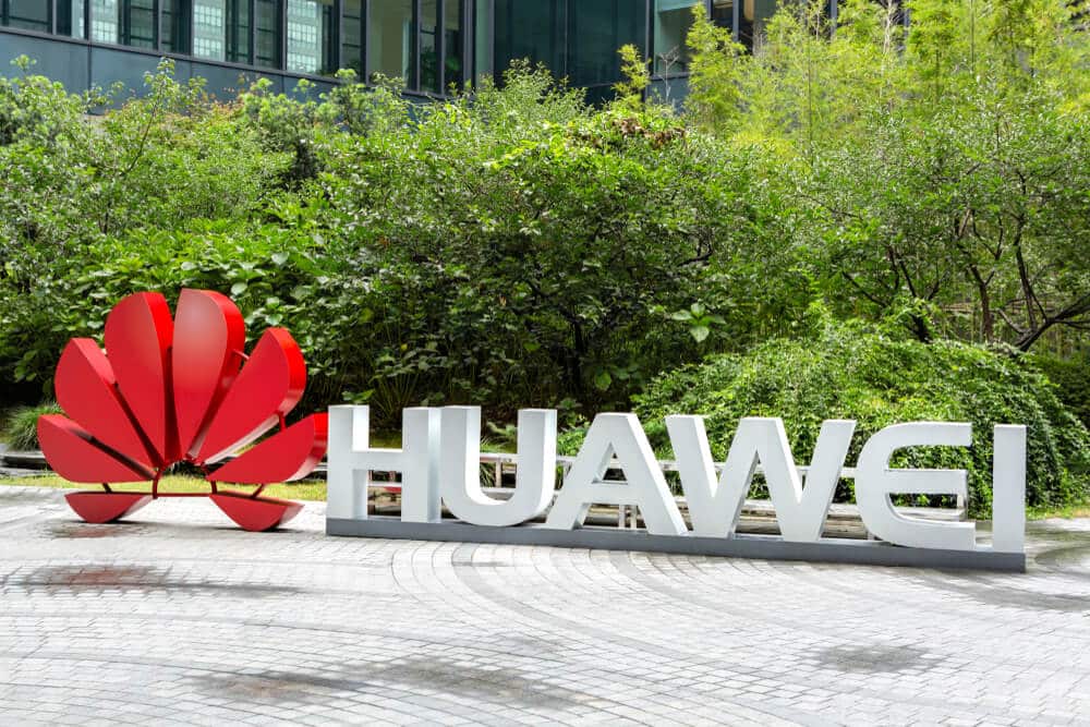 Huawei: Huawei company logo on the floor with plants background.