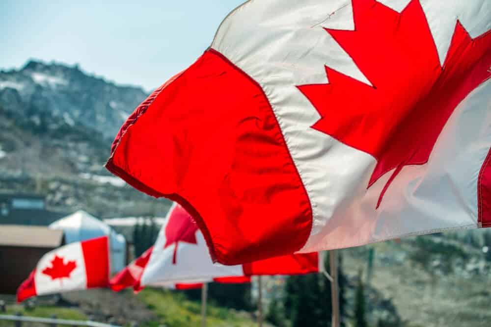 Banderas de Canadá ondeando en el viento en un escenario montañoso.